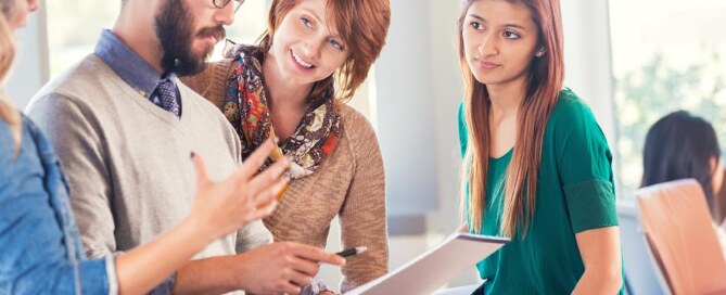 Coworkers in office gather around and discuss ideas
