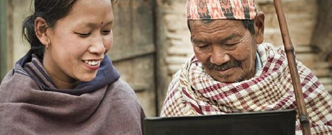 Man and woman look at laptop outdoors