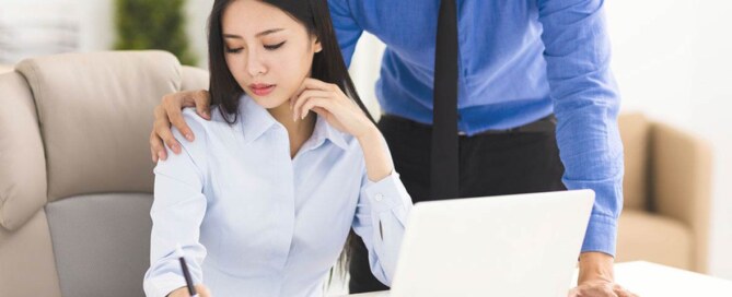 Male employee harasses his female colleague, placing his hand on her shoulder