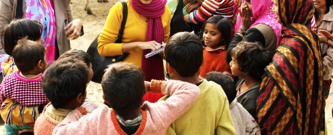 Two female social workers interact with a group of villagers in India