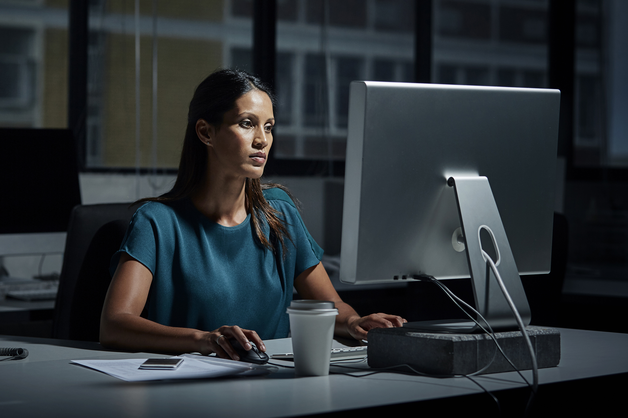 Businesswoman uses computer in dark office