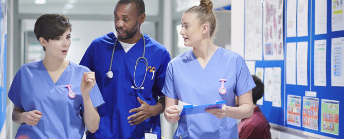 Medical consultant and two nurses walk along a hospital corridor
