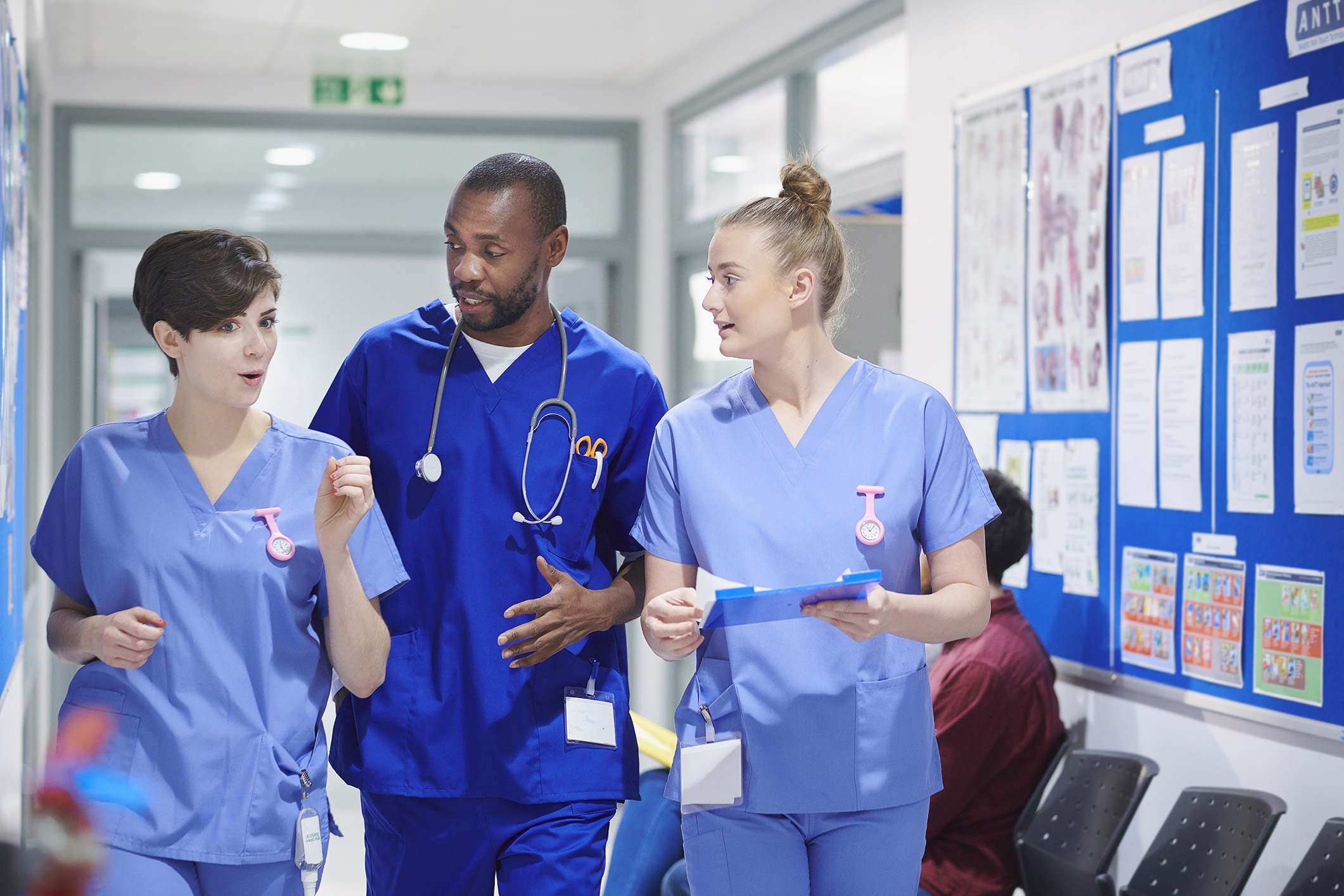 Medical consultant and two nurses walk along a hospital corridor