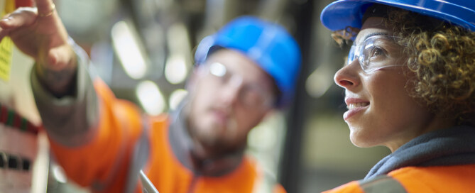 Two industrial service engineers conduct a safety check of a control panel and boiler room at a power station