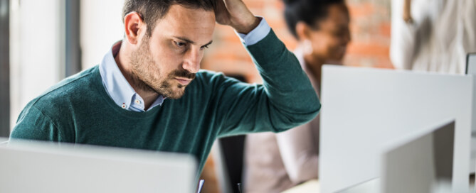 Young worried businessman works on laptop at corporate office
