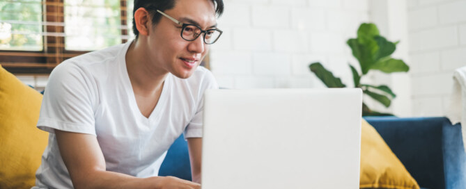 Young Asian man works with laptop at home