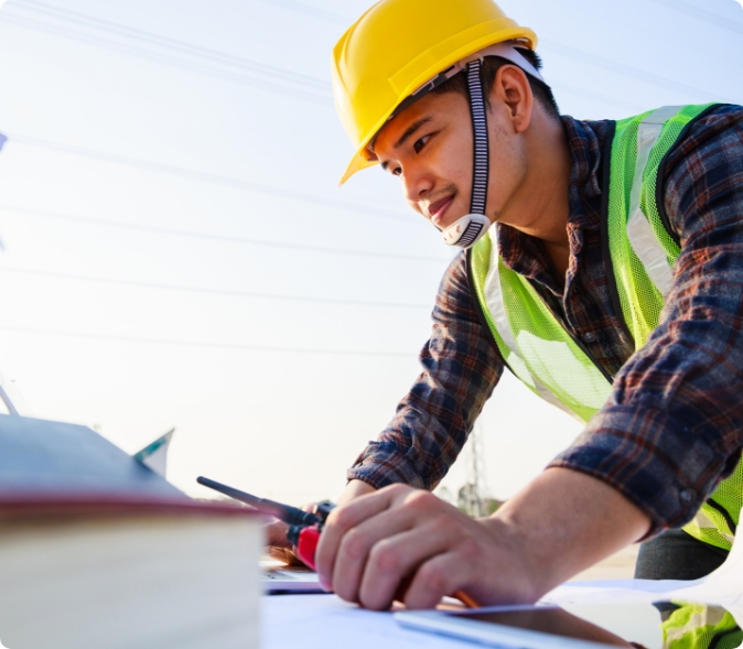 Male construction worker in hardhat draws on corporate learning experiences while reviewing project specifications
